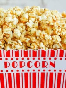 A overflowing popcorn container piled high with Lemon Thyme Caramel Corn.