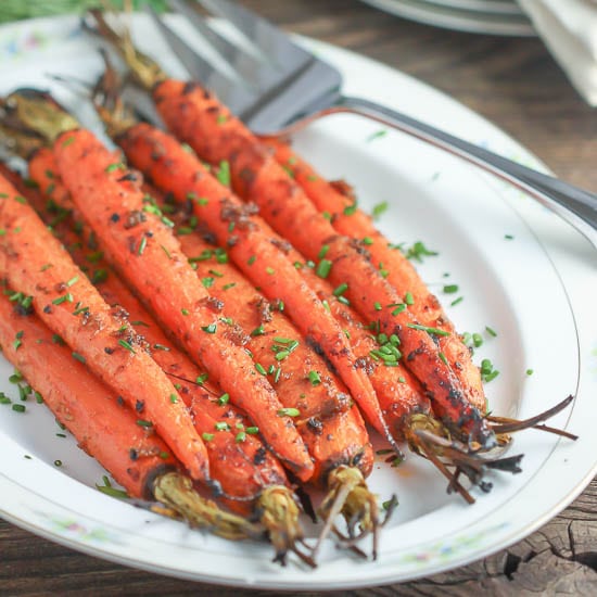 Roasted Carrots with Miso Butter sprinkled with chives on a white platter.
