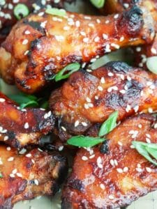 Close up shot of Crispy Asian Chicken Wings sprinkled with sesame seeds and sliced scallions.