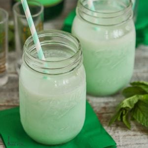 Boozy Shamrock Shakes served in mason jars with green and white striped straws.