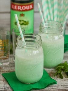 Boozy Shamrock Shakes served in mason jars with green and white striped straws.