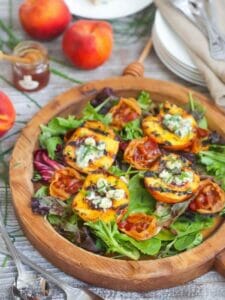 Grilled Peach Salad with Honey Vinaigrette on a round wood serving board.
