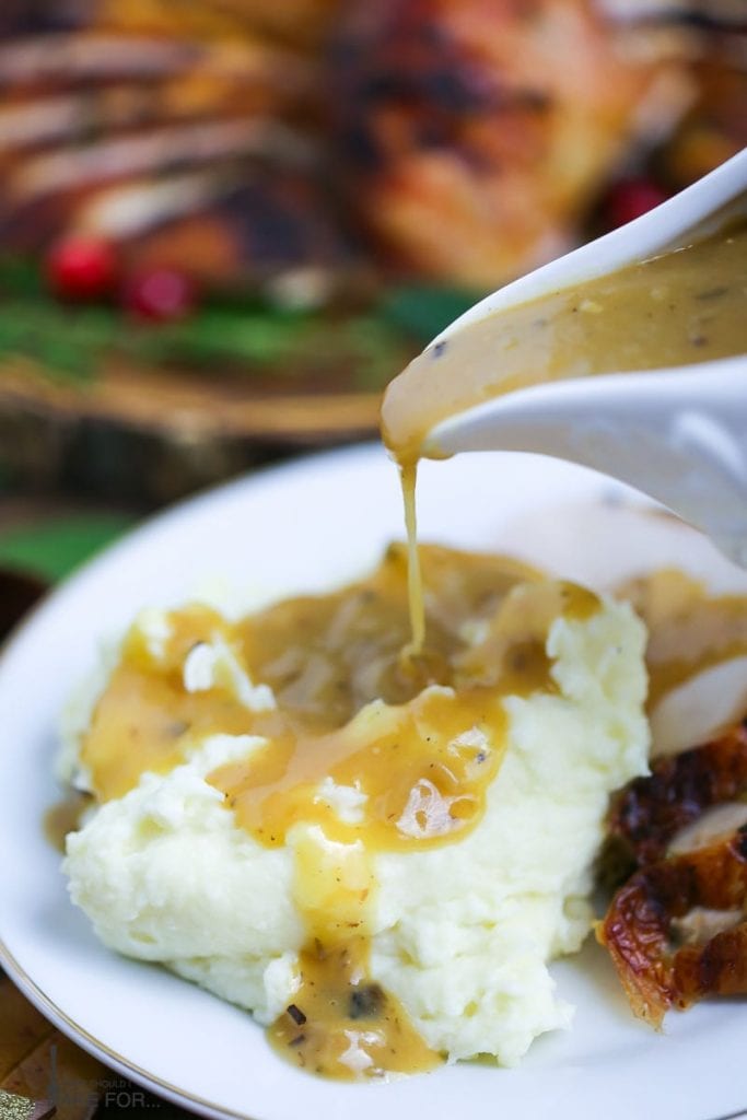 Cider gravy is poured from a gravy boat over a serving of mashed potatoes.