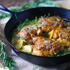 A cast iron skillet with crispy chicken thighs in creamy lemon and herb sauce.