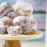 New Orleans Beignets piled on a parchment lined cake stand.