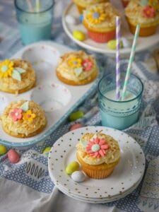 Toasted Coconut Cupcakes on a cake stand, cute muffin tin, and on a stack of polka dot plates with blue glasses full of milk.