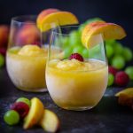 Close up shot of Peach Sangria Slushies garnished with peach wedges.