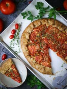 Tomato Galette on a baking sheet with a slice cut out and on a small plate.