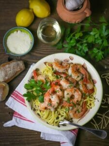 Overheard shot of Easy Shrimp Scampi in a bowl with wine, lemon, garlic and parm on the table.