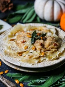Butternut Squash Ravioli with pumpkins and sage leaves around.