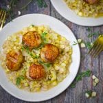 Close up shot of a serving of seared scallops over creamy fresh corn risotto.