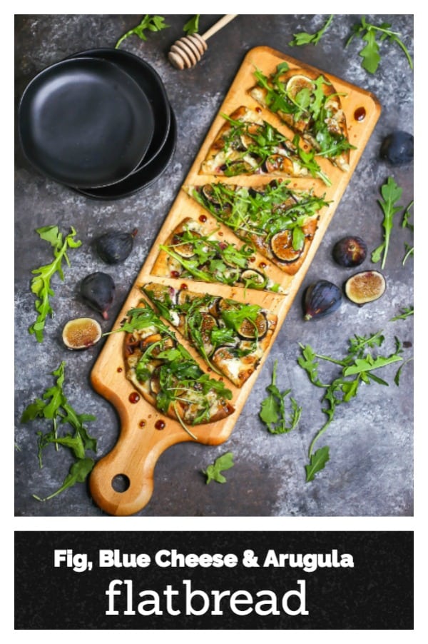 Fig, blue cheese, and arugula flatbread sliced and served on a wooden cutting board.