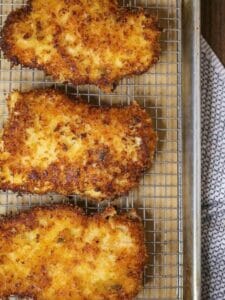 Close up of breaded chicken breasts cooling on a wire rack.