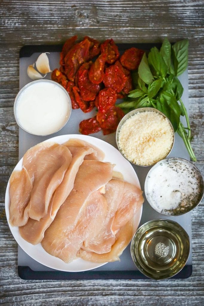 Gather ingredients for chicken with creamy sun-dried tomato sauce including thick cut chicken breasts, garlic, sun-dried tomatoes, basil, parmesan cheese, wine and seasonings.