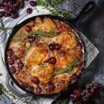 Braised Chicken with Grapes in a cast iron skillet with sprigs of thyme scattered around.
