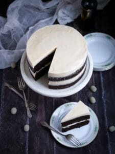 Chocolate Stout Cake with Baileys Buttercream with a slice cut out on a cake stand and the cake slice on a plate with a fork.