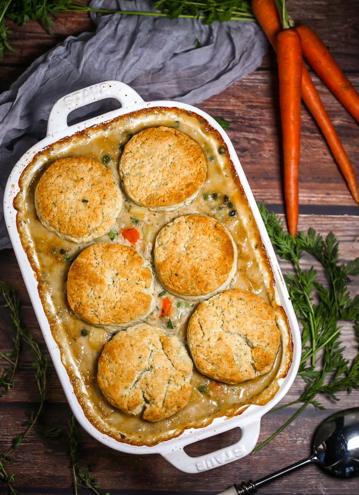 Vegetable Pot Pie with Biscuit Topping in a white baking dish with carrots alongside.