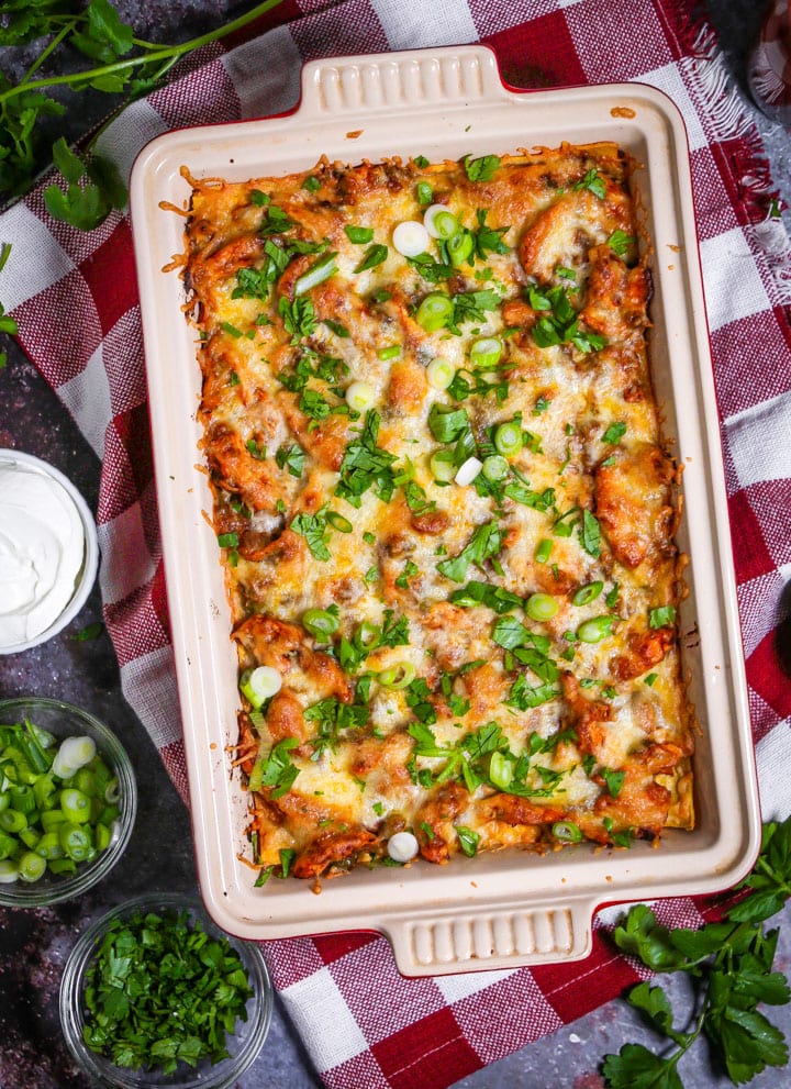Easy Chicken Enchilada Casserole in a baking dish sprinkled with scallions and cilantro.