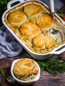 Vegetable Pot Pie with Biscuit Topping in a white baking dish with a serving in a small white bowl.