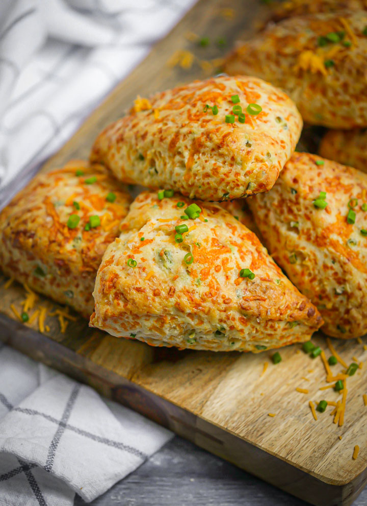 Cheddar Chive Scones on a wood board sprinkled with chives.
