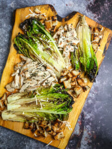 Grilled Chicken Caesar Salad presented on a wood board.