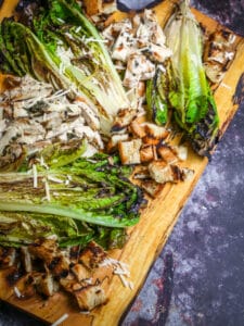 Grilled Chicken Caesar Salad presented on a wood board.
