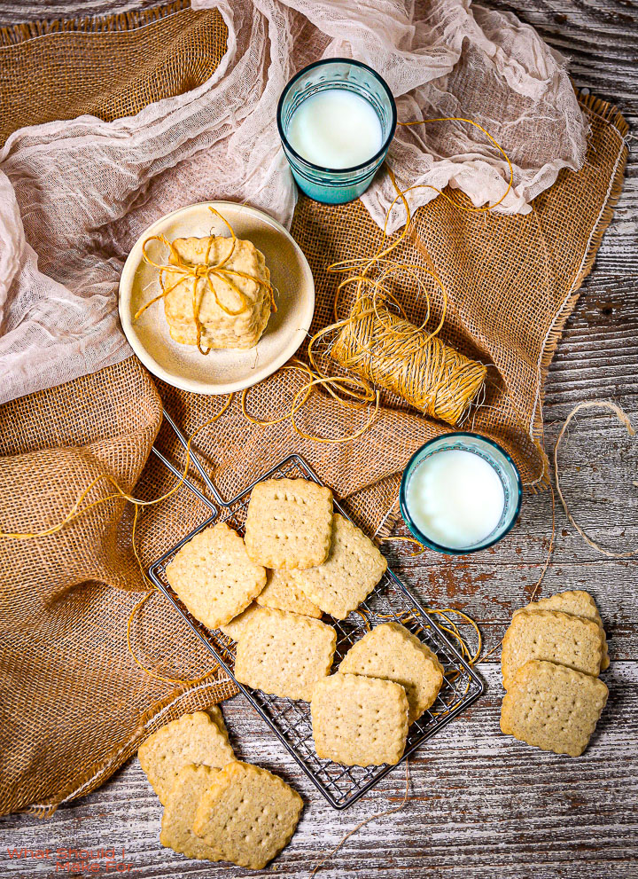 Classic Shortbread Cookies on burlap with a roll of twine, glasses of milk and a white towel.