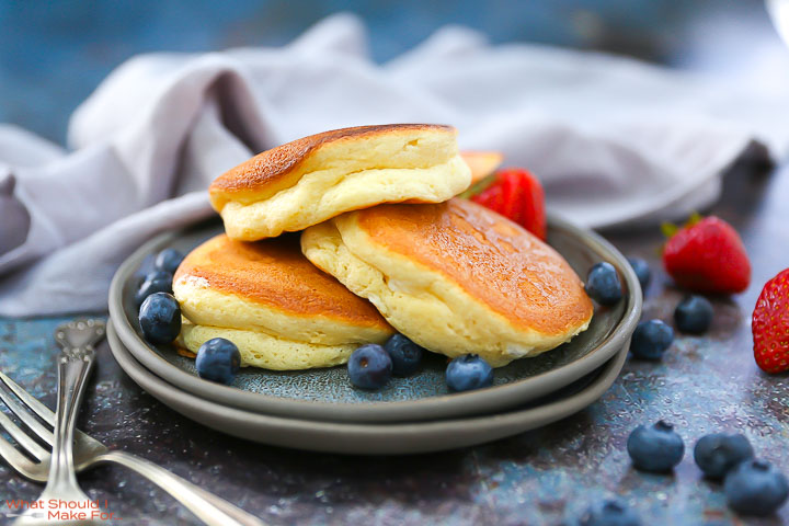 Fluffy Japanese Pancakes on plate with blueberries and strawberries around.