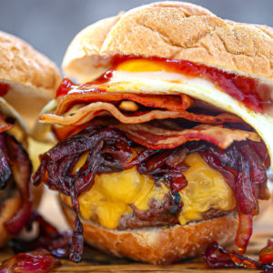 Close up of a Egg Topped Bacon Cheeseburger piled high with sautéed onions.