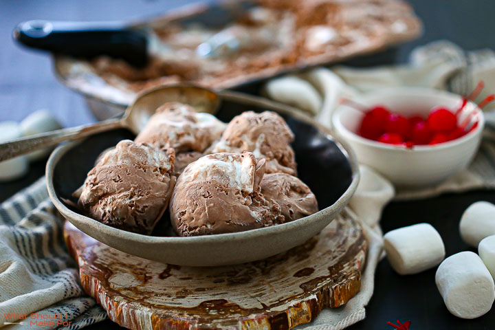 Chocolate Marshmallow Swirl Ice Cream in a shallow bowl with toppings in dishes alongside.