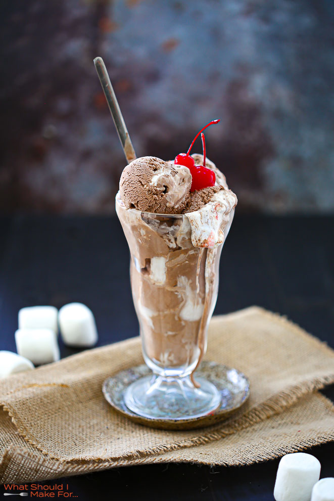 Chocolate Marshmallow Swirl Ice Cream in a tall glass dish topped with cherries.