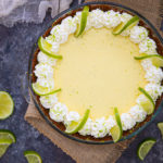 Overhead shot of a key lime pie decorated with whipped cream and fresh limes.