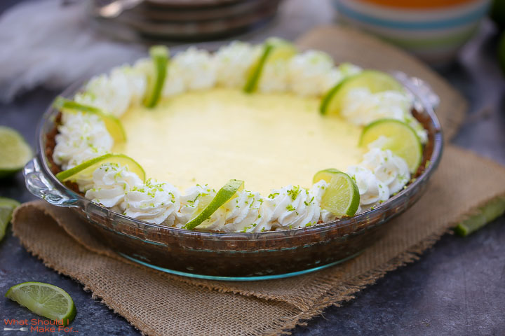 Close up of a key lime pie decorated with whipped cream and fresh limes.