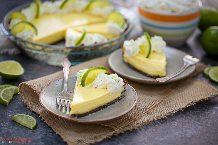 A slice of Key Lime Pie on a plate with the cut pie in the background.
