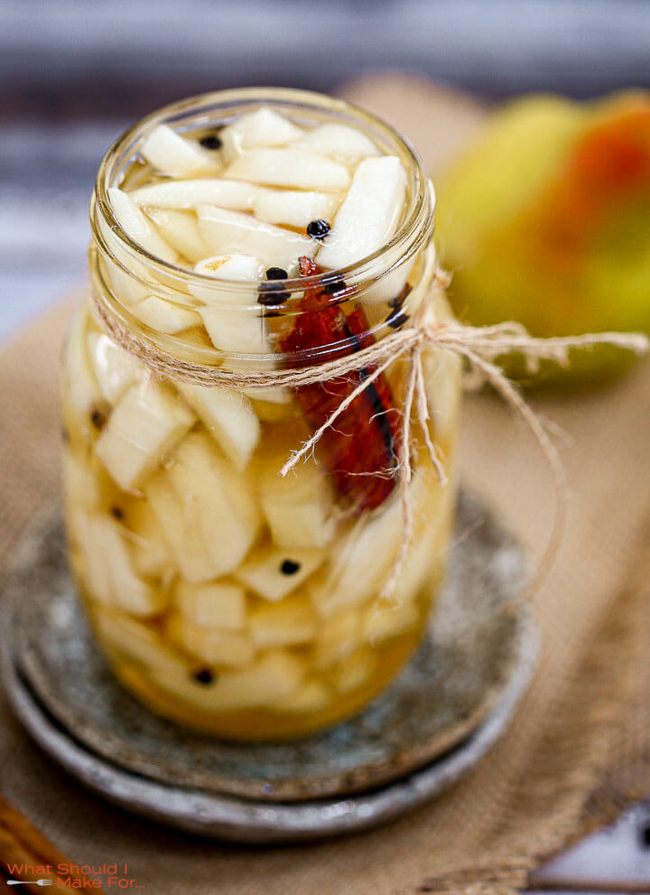 Quick Pickled Pears in a mason jar with cinnamon sticks and a pear in the background,