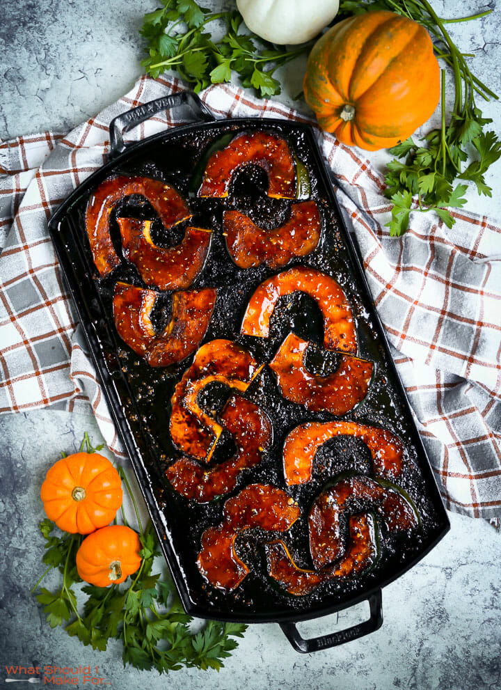 Sweet and Spicy Acorn Squash on a long griddle pan with pumpkins scattered around.