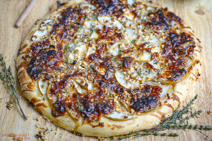 Close up of a Pear and Brie Pizza with thyme scattered around.