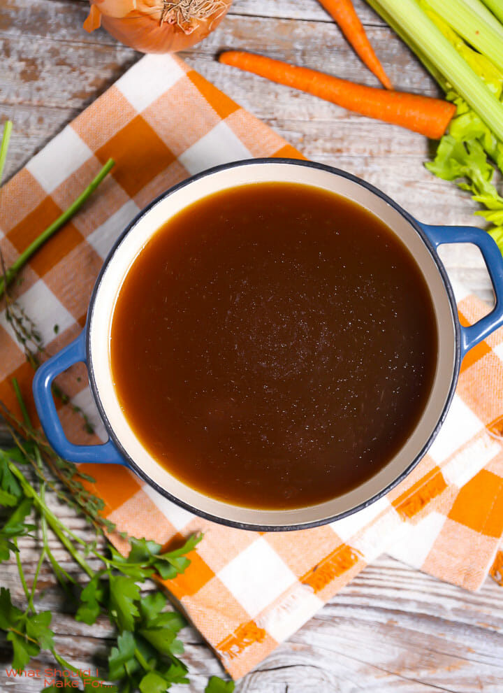 Homemade Turkey Stock in a the pot on top of an orange checkered table linen.