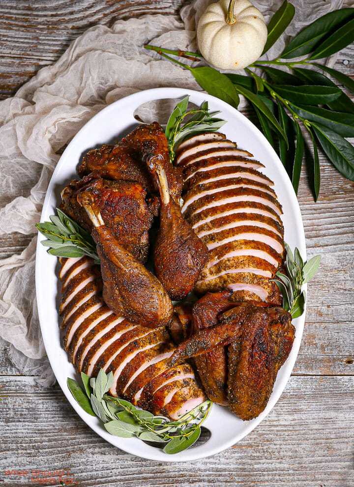 Roast Turkey in Parts carved and presented on a white oval serving platter with sage.