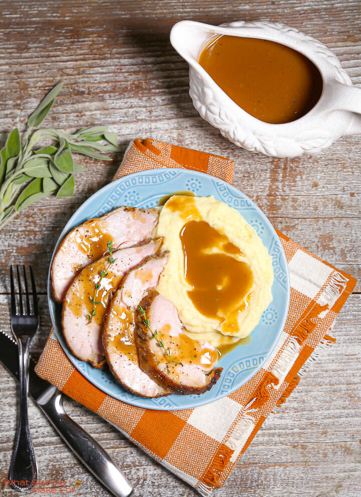 Make-ahead turkey gravy in a gravy boat and served over turkey and mashed potatoes.