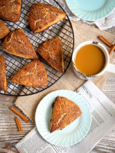 Cinnamon Sugar Scones on a round wire rack wit one scone on a plate with a cup of coffee.
