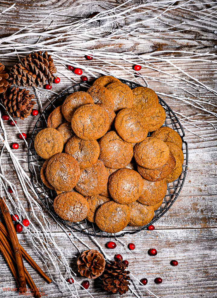 Soft Molasses Cookies on a round wire rack with white branches and pine cones around.