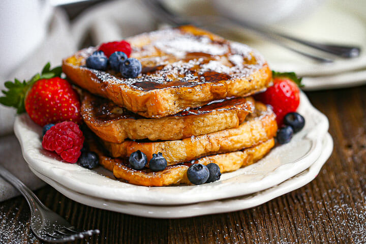 Brioche French Toast drizzled with syrup and served with berries.