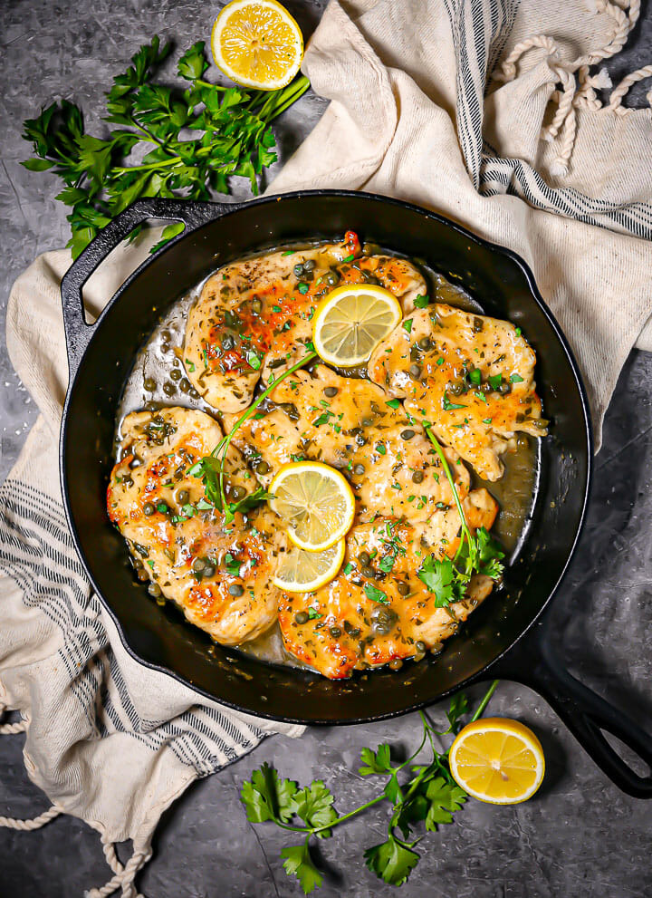 Chicken piccata in a cast iron skillet on top of a striped linen.