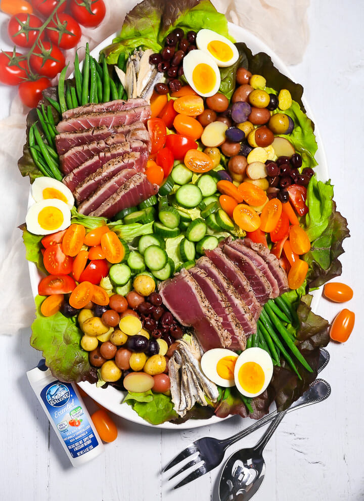 A composed Seared Tuna Nicoise Salad on a platter with a salt shaker next to it.