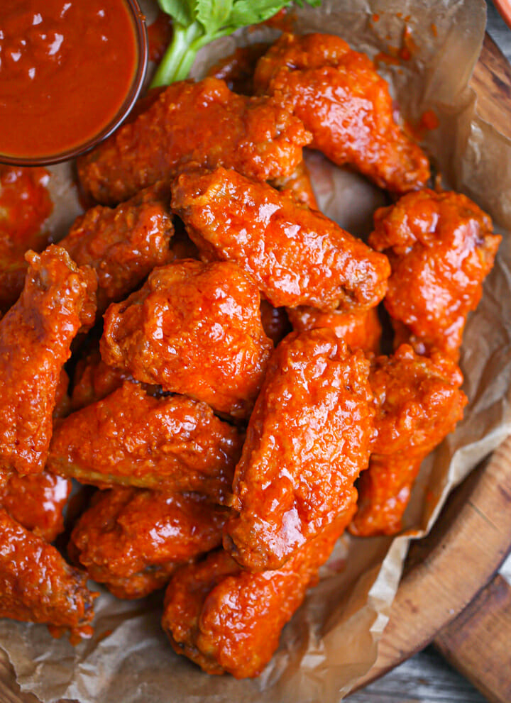 Close up of baked buffalo wings with a extra wing sauce.