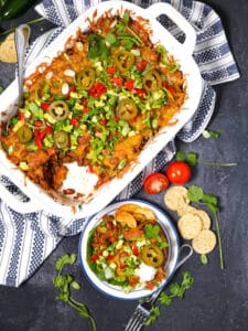 Beef Taco Casserole with a scoop taken out and placed on a serving plate with chips and tomatoes scattered around.