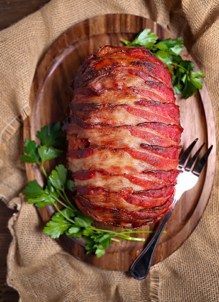 Overhead shot of Bacon-Wrapped Meatloaf on an oval wood serving board.