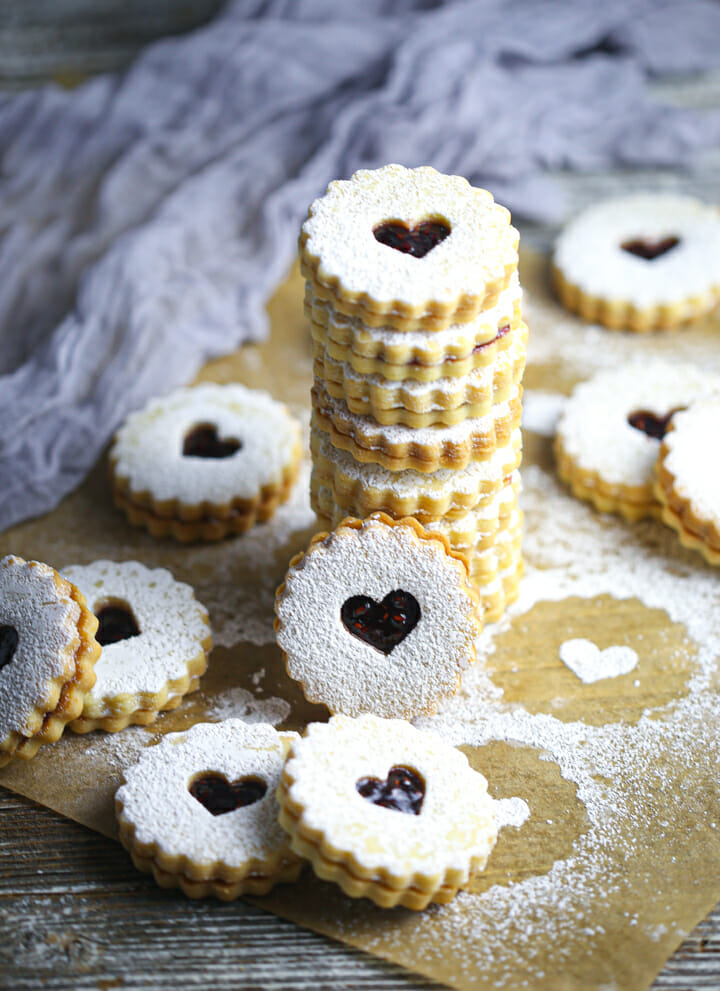 A stack of Nut-Free Linzer Cookies with other cookies scattered around.
