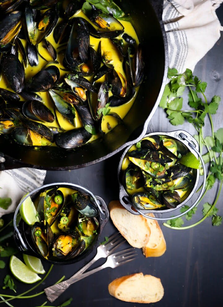 Two servings of Curry Coconut Mussels with sliced bread for dipping.